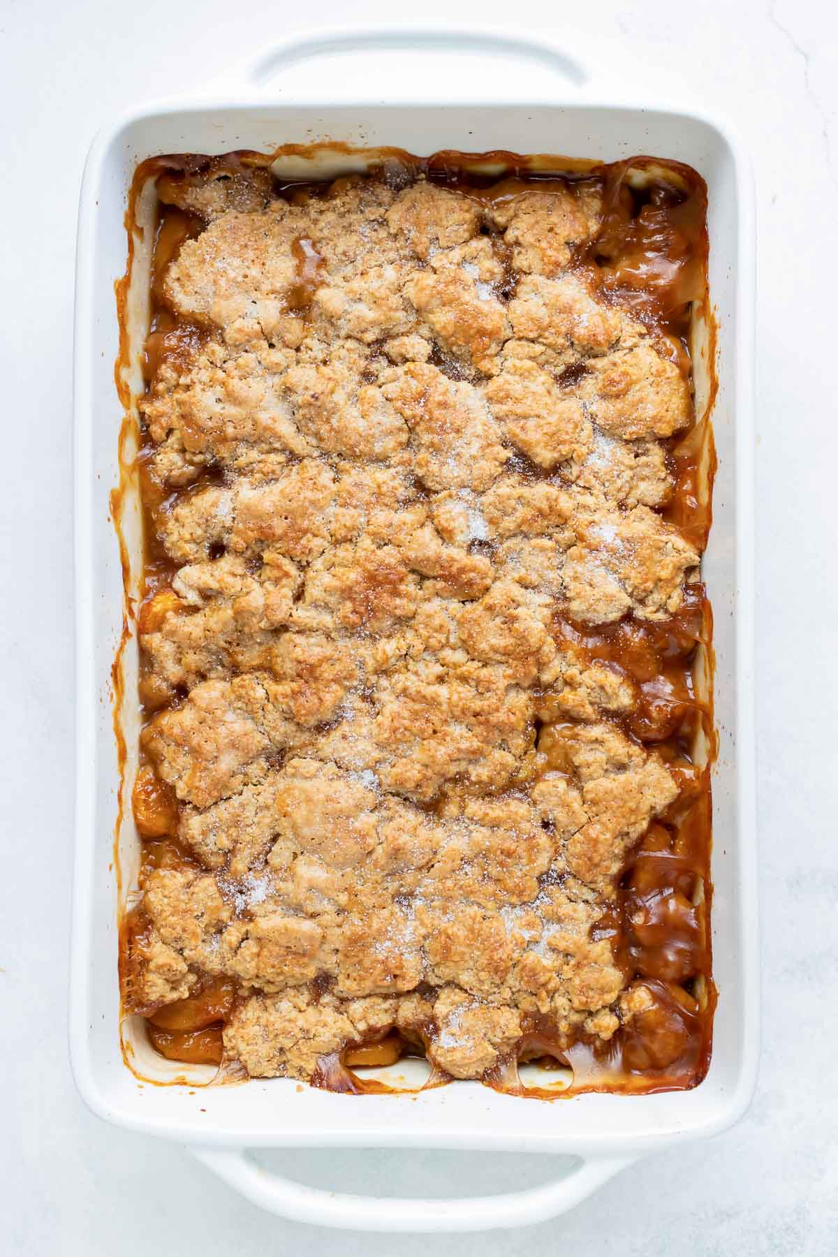 Fully baked peach cobbler is ready to enjoy.