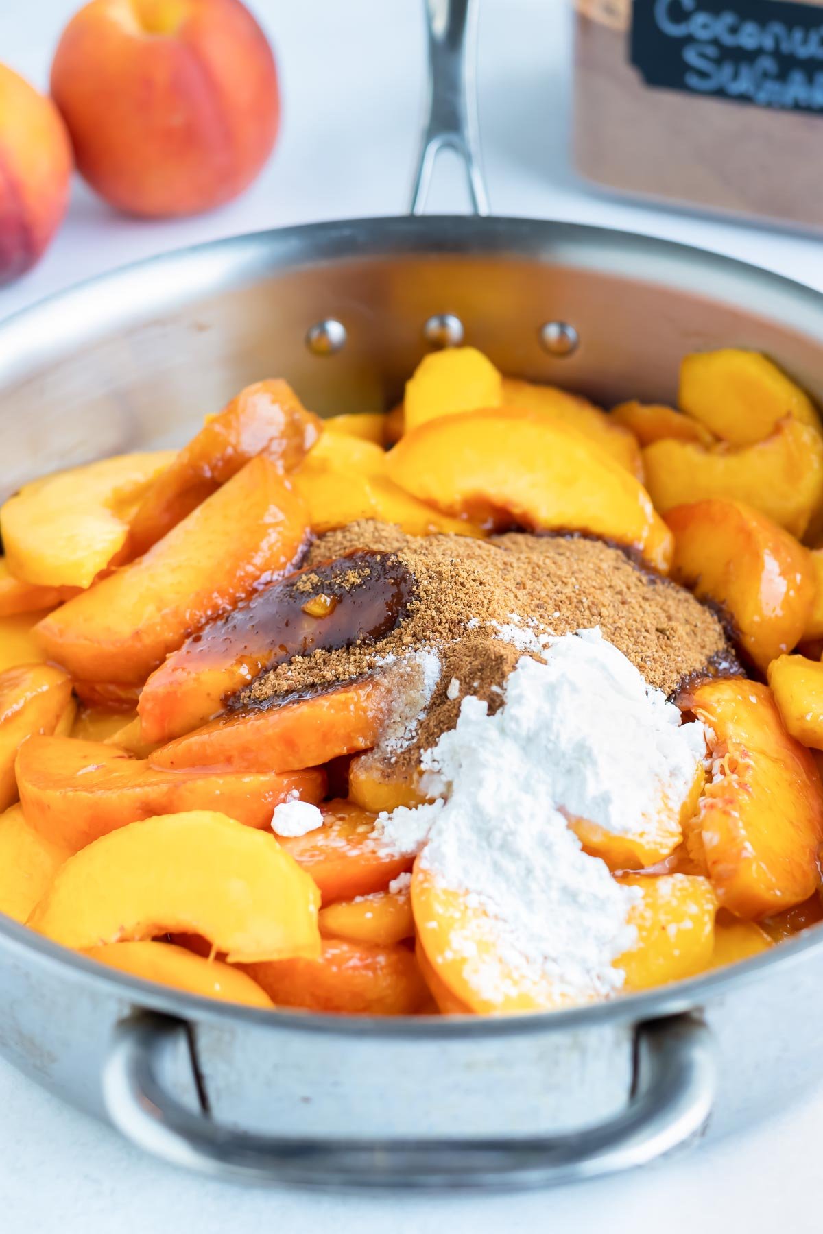 Peaches, sugar, and cinnamon are added to a saucepan.