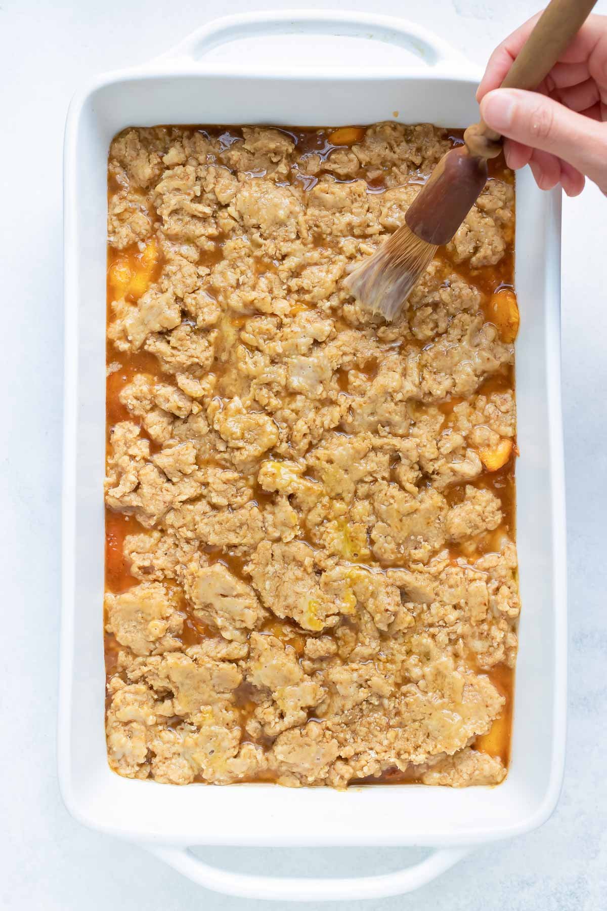 An egg wash is brushed over the cobbler topping.