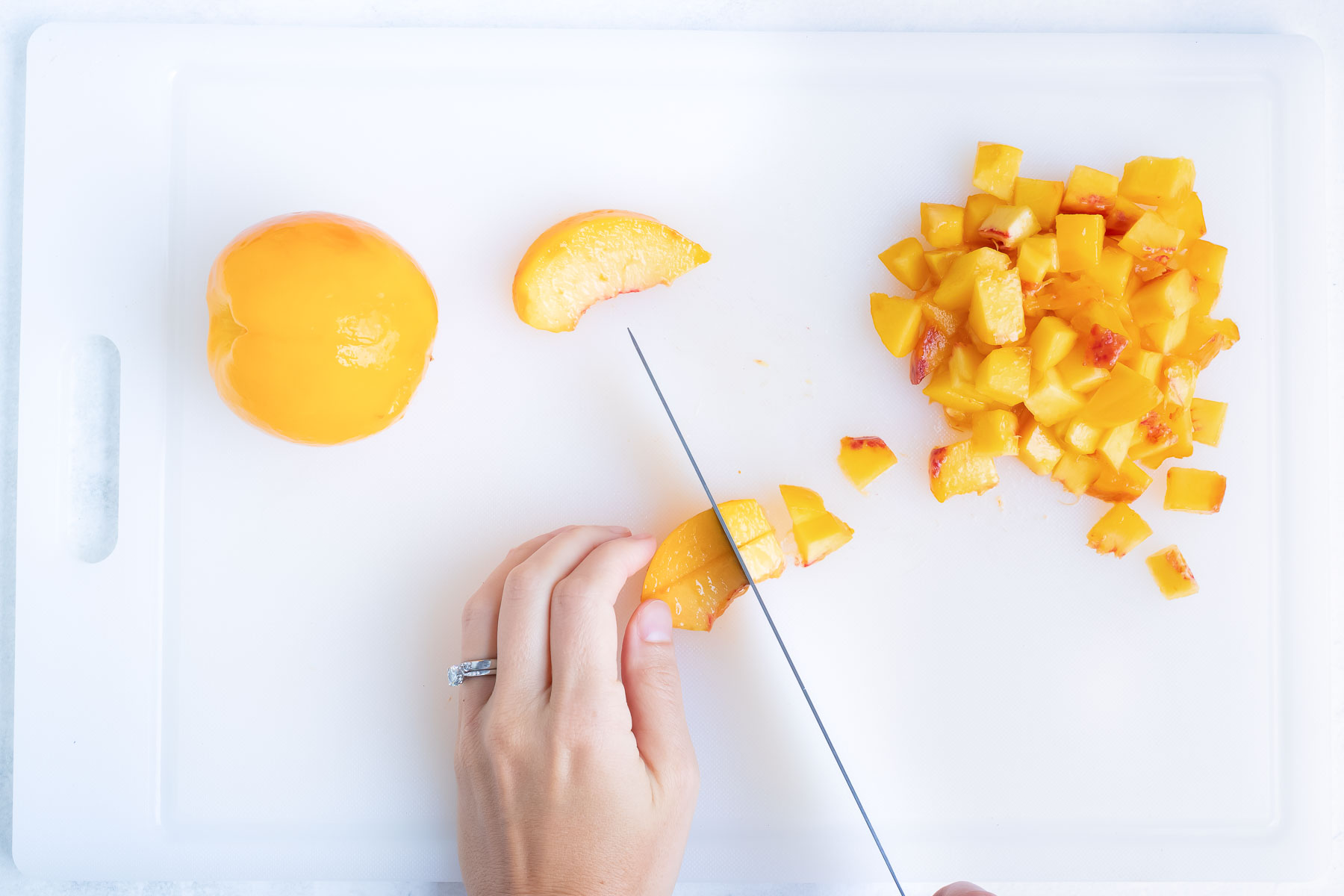 A sharp knife chops fresh peaches.