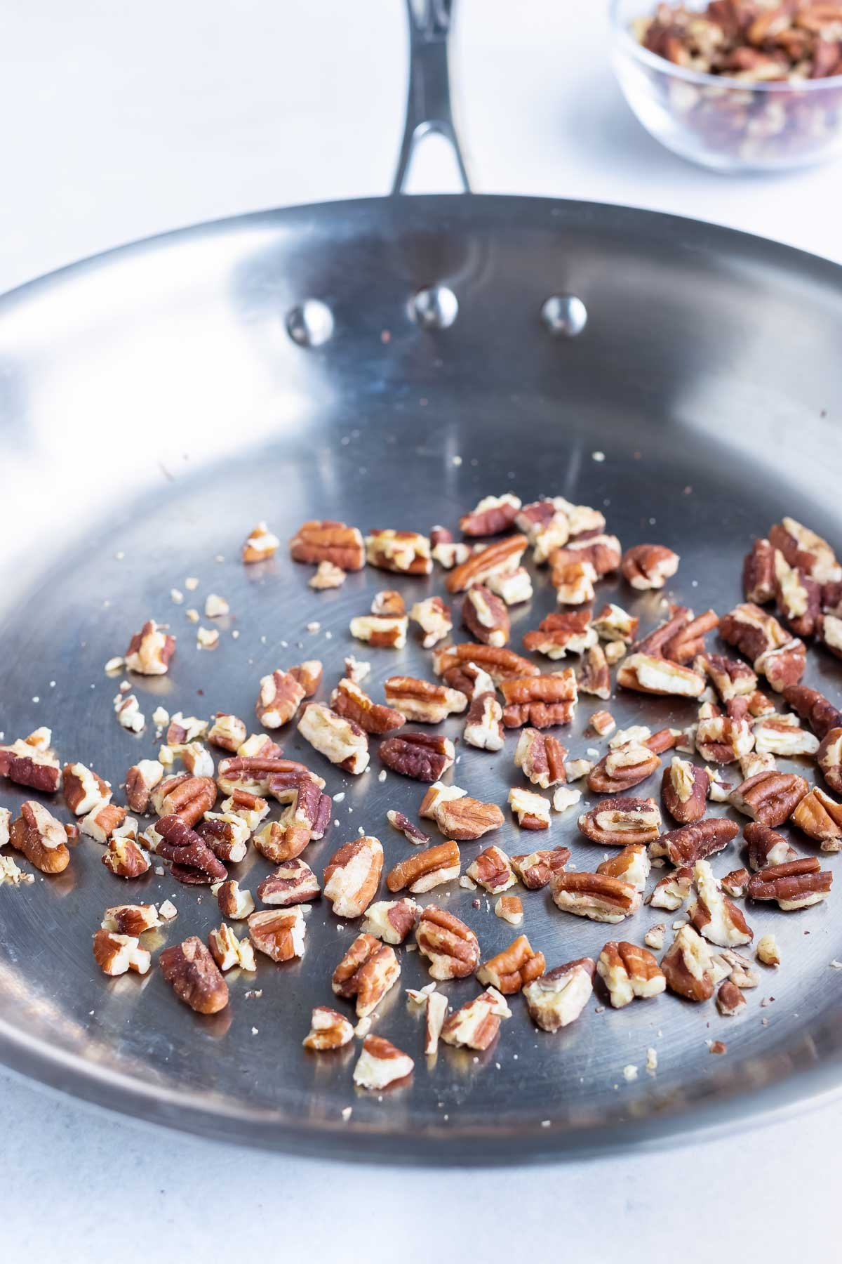 Pecans are toasted in a pan.