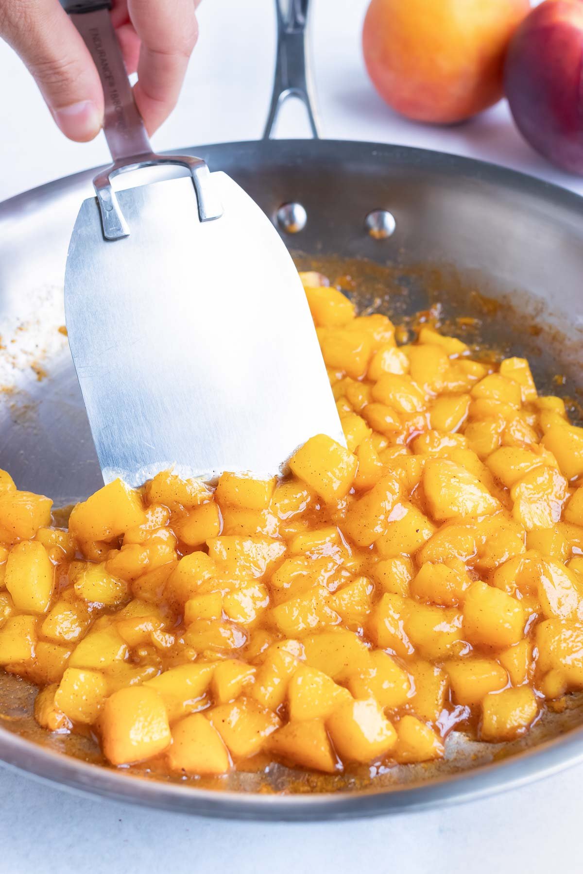 Peaches are cooked in a skillet.