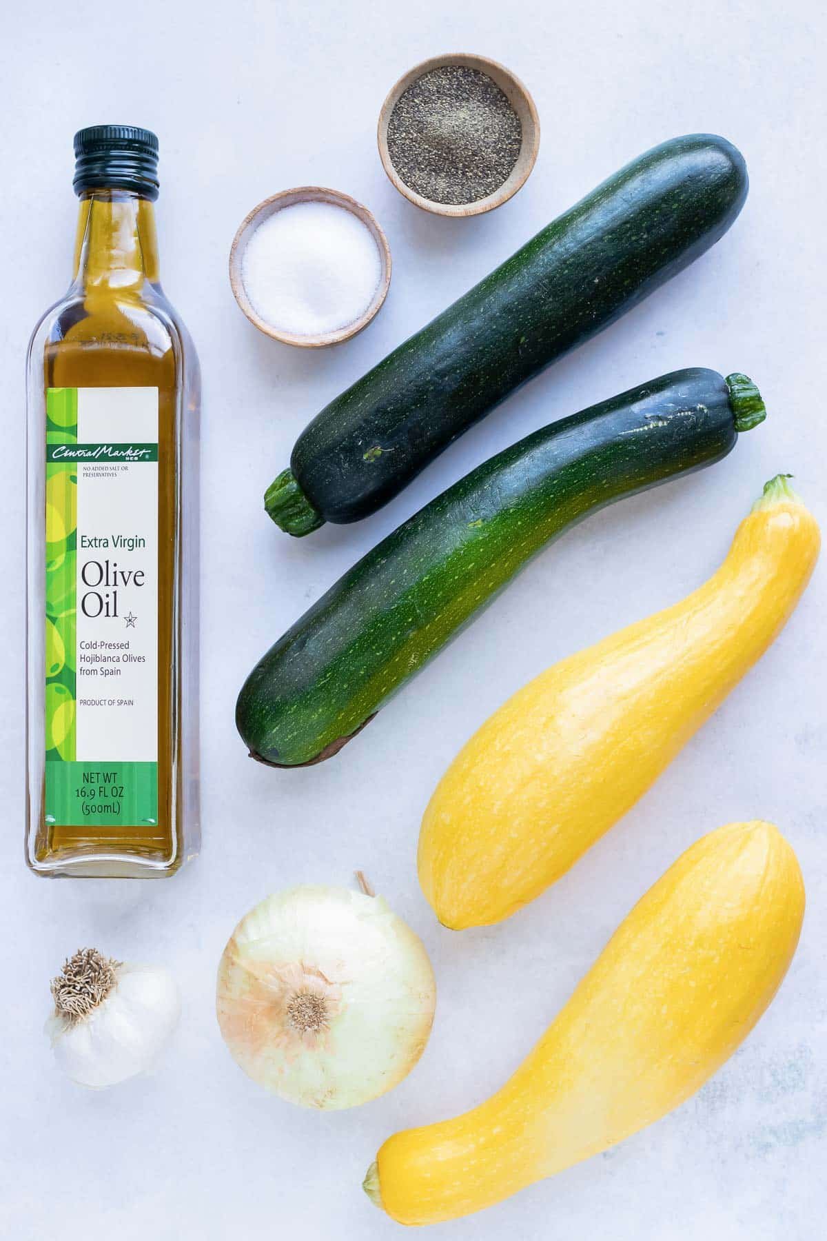 Zucchini, yellow squash, salt, pepper, onion, oil, and garlic ingredients for a side dish recipe.