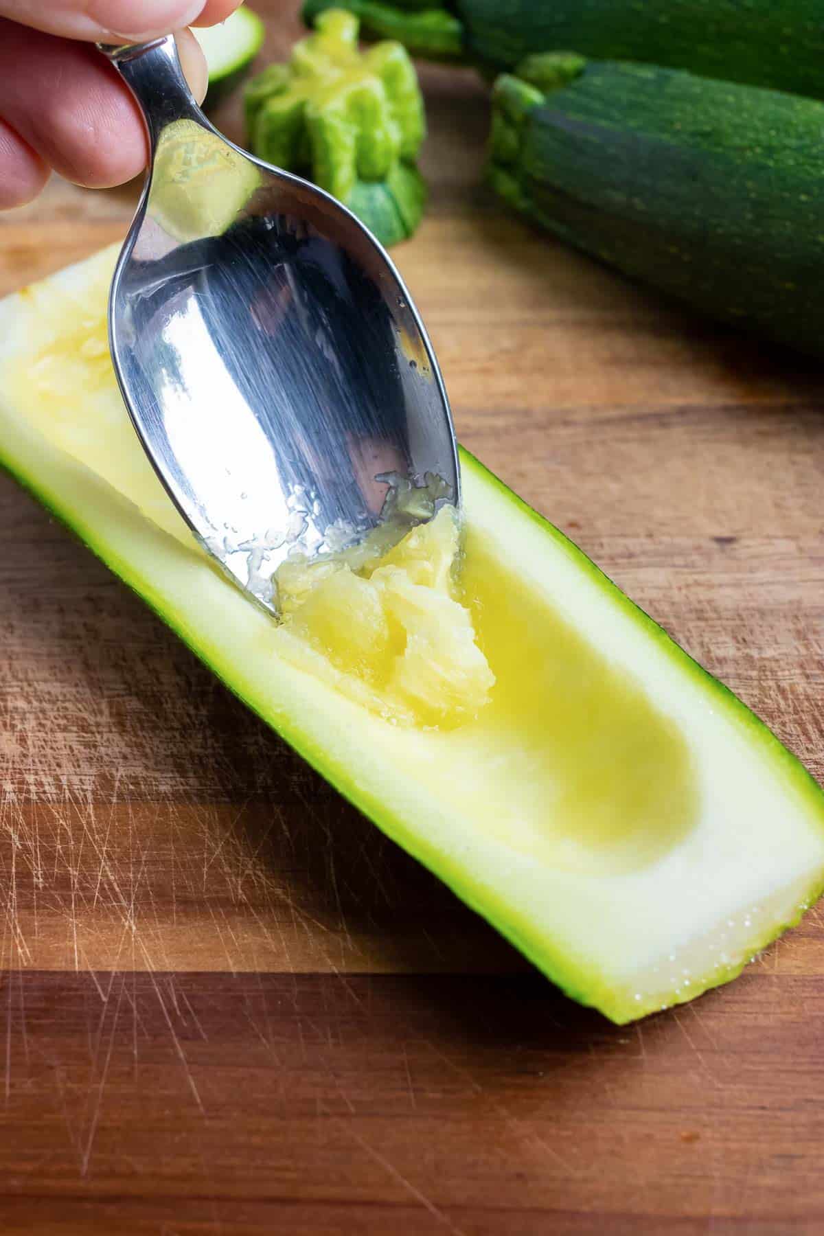 A spoon is used to scoop out some of the flesh of a zucchini.