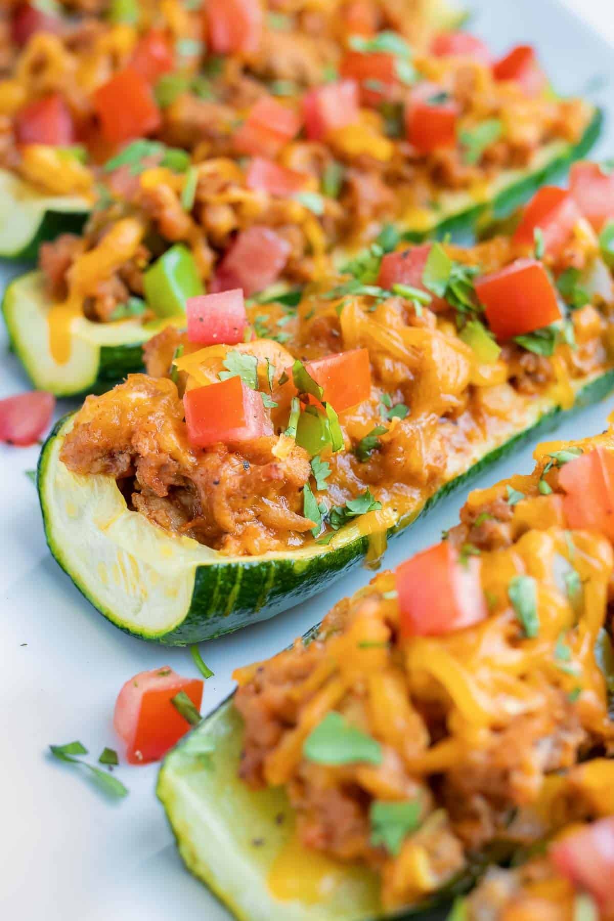 A zucchini squash that has been made into a boat and stuffed with ground beef and taco filling.