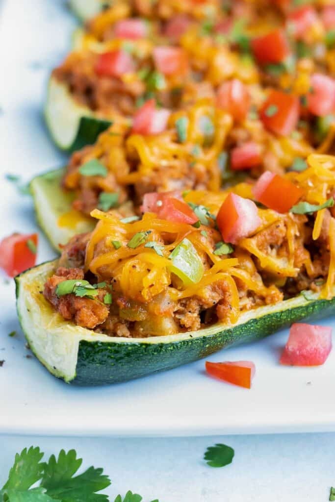 Zucchini boats are stuffed with a taco filling on a tray.