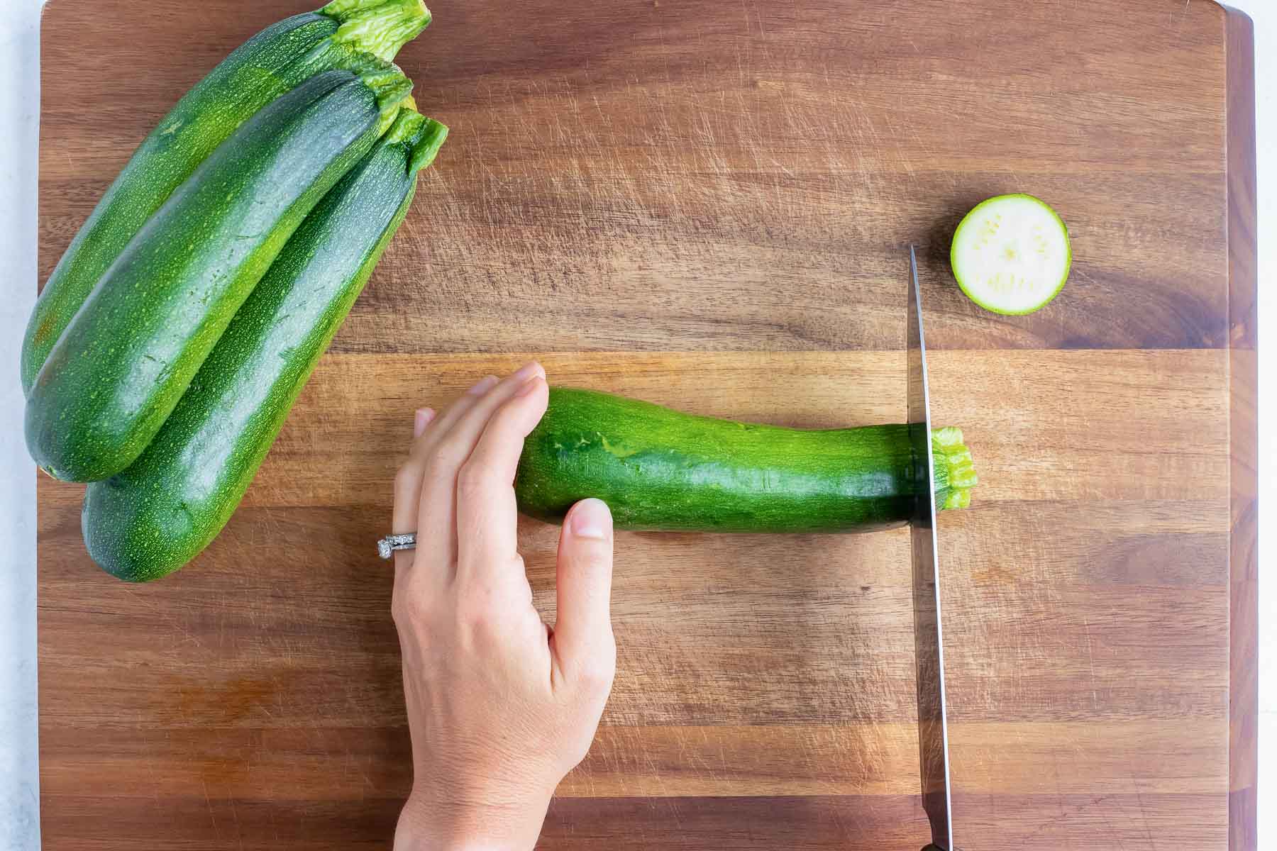 The ends of a zucchini are sliced off.