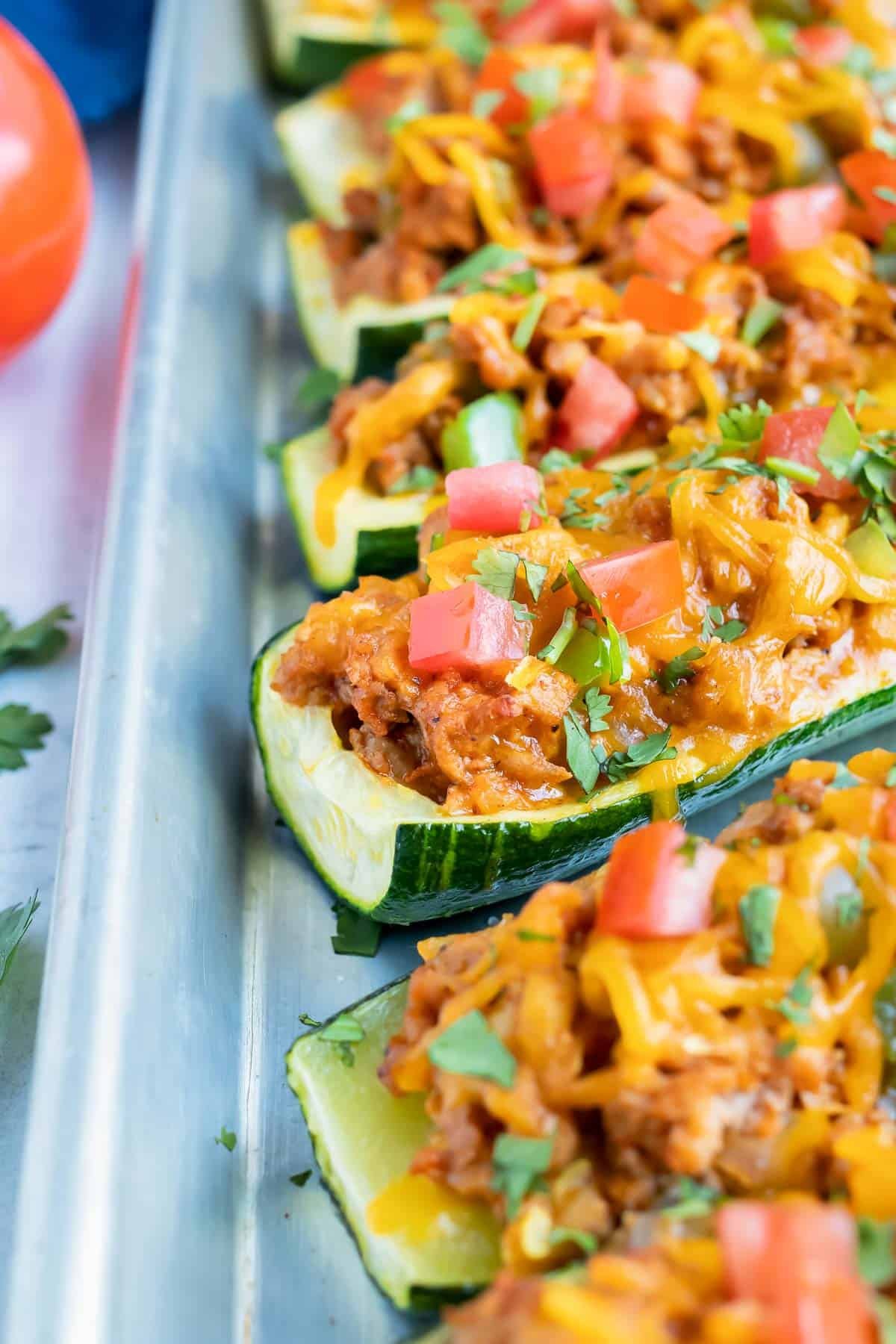 Taco stuffed zucchini boats with ground turkey on a baking sheet.