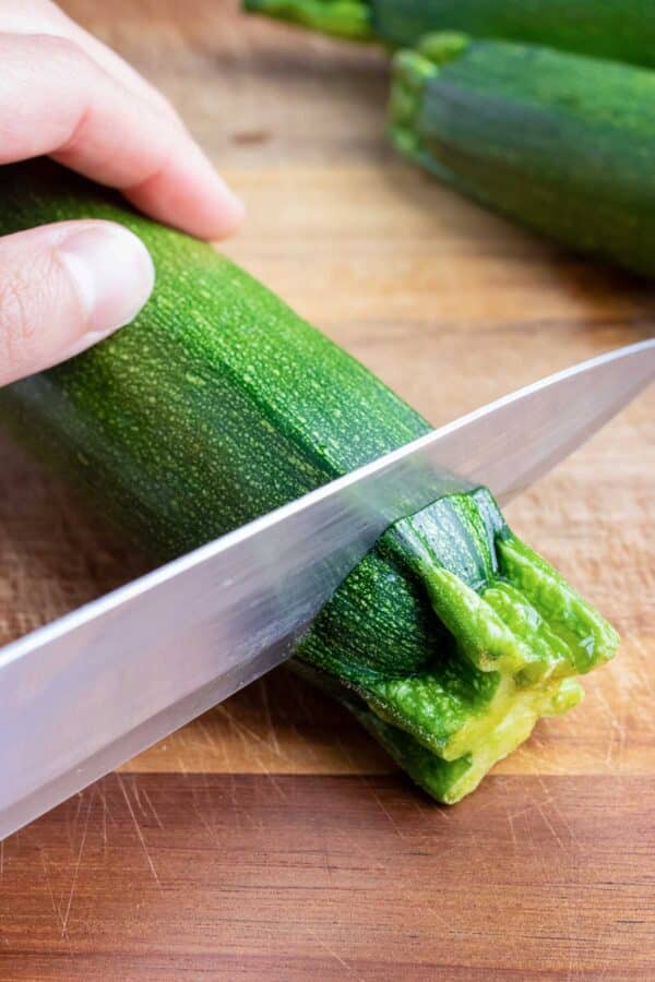 The ends of a zucchini are sliced off.