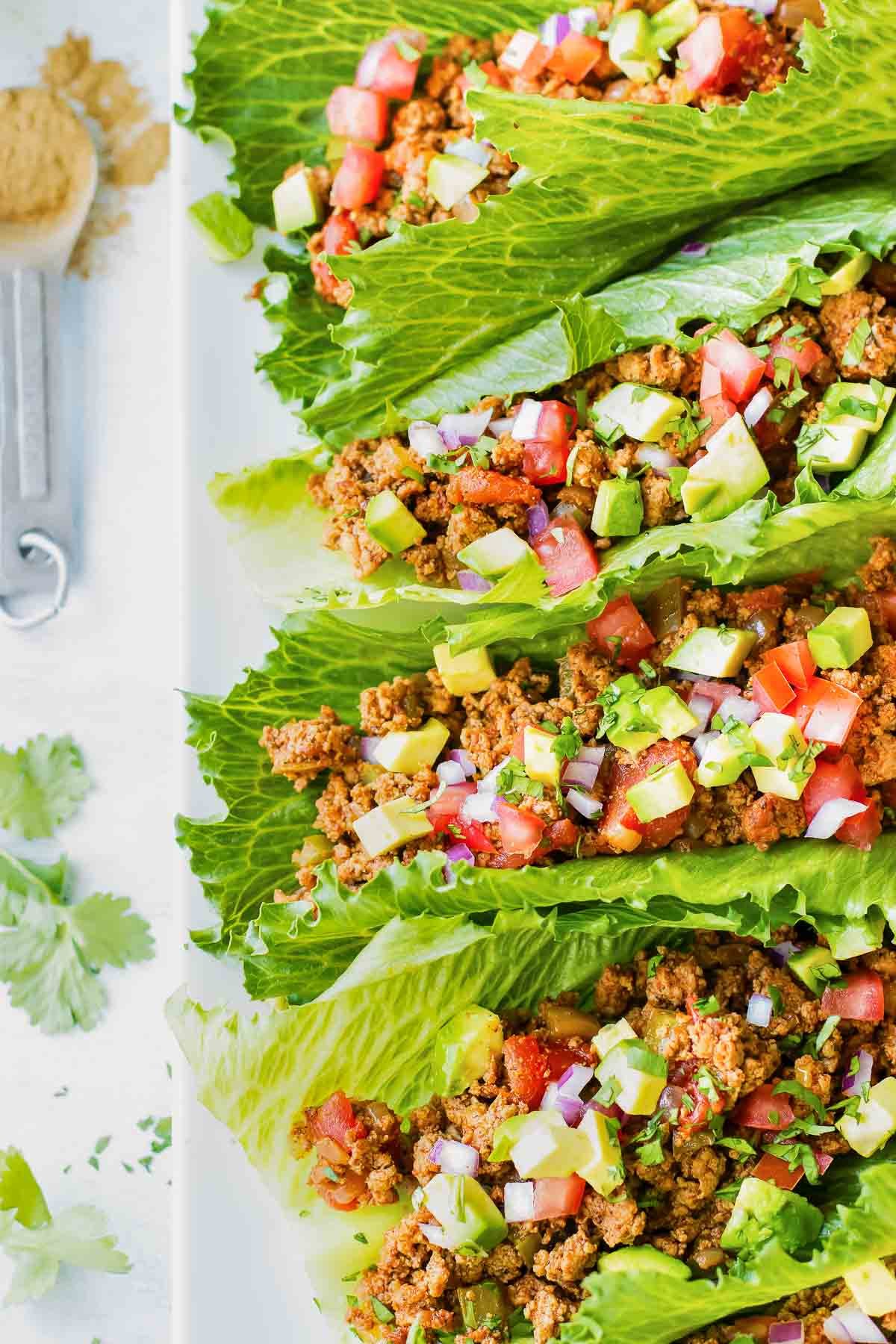 A row of taco lettuce wraps on a white plate.