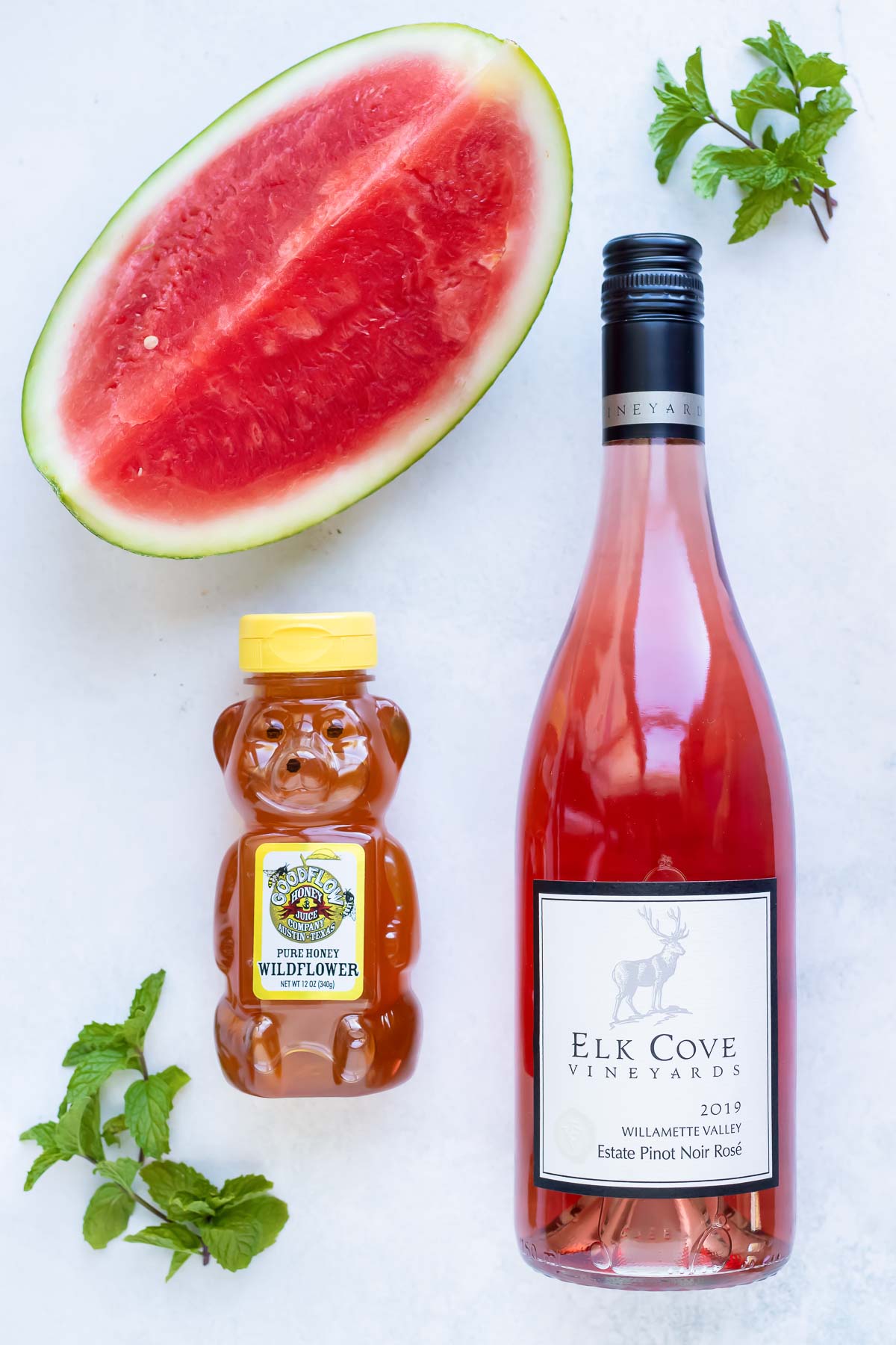 Rose wine, watermelon, honey, and mint as the ingredients needed for a frosé recipe.