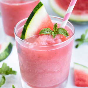 Watermelon Frosé with mint in a glass with a pink straw for a frozen summer cocktail.