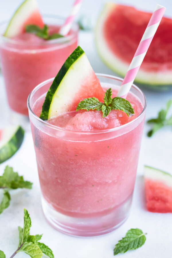 Watermelon Frosé with mint in a glass with a pink straw for a frozen summer cocktail.