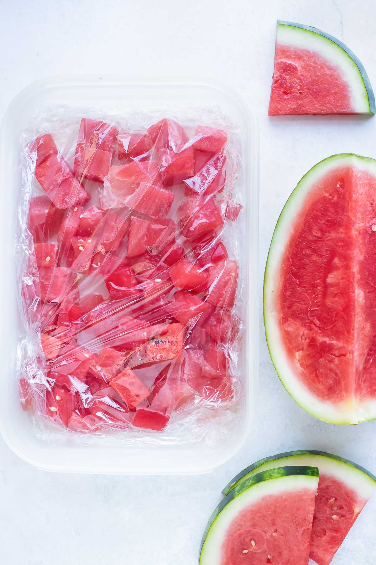 Frozen watermelon chunks in a freezer safe palstic container.