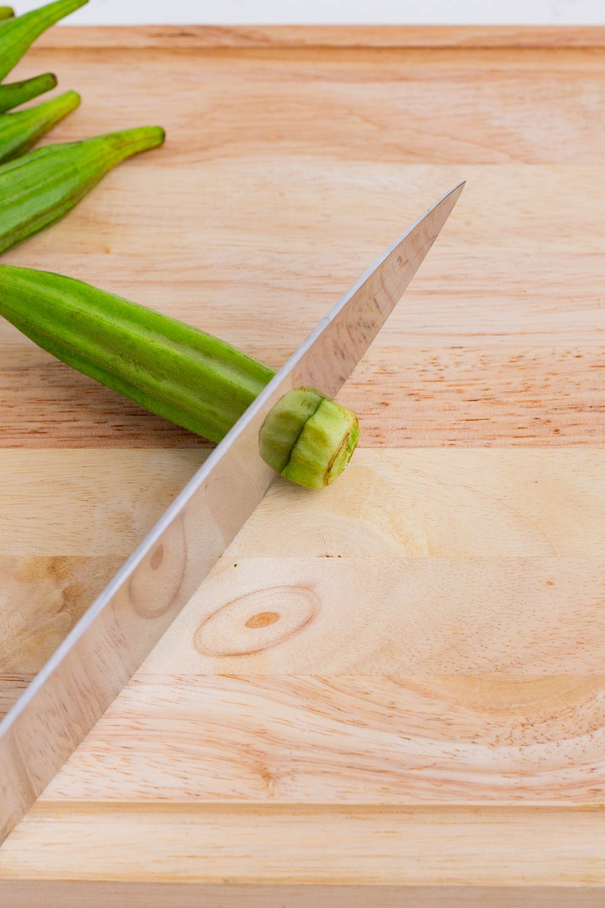 A sharp knife slices an okra pod.