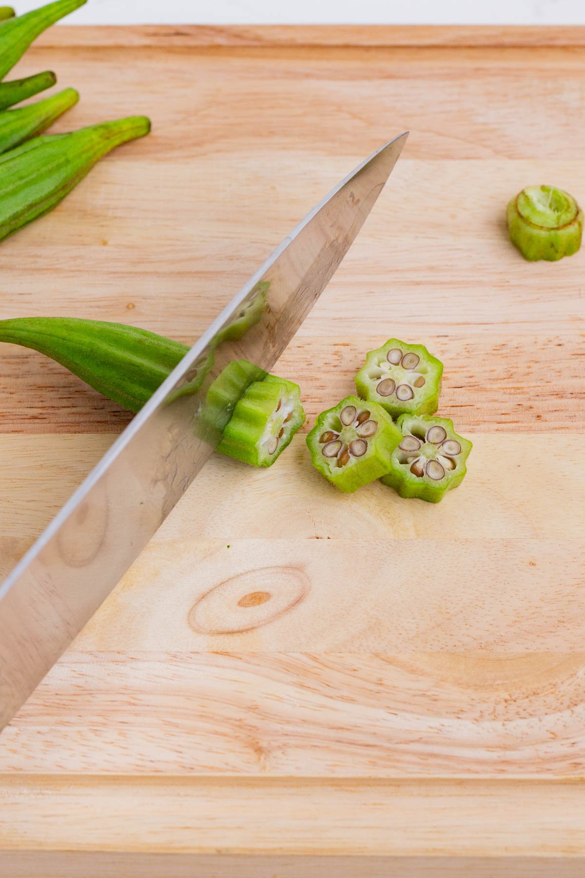 A sharp knife slices an okra pod.