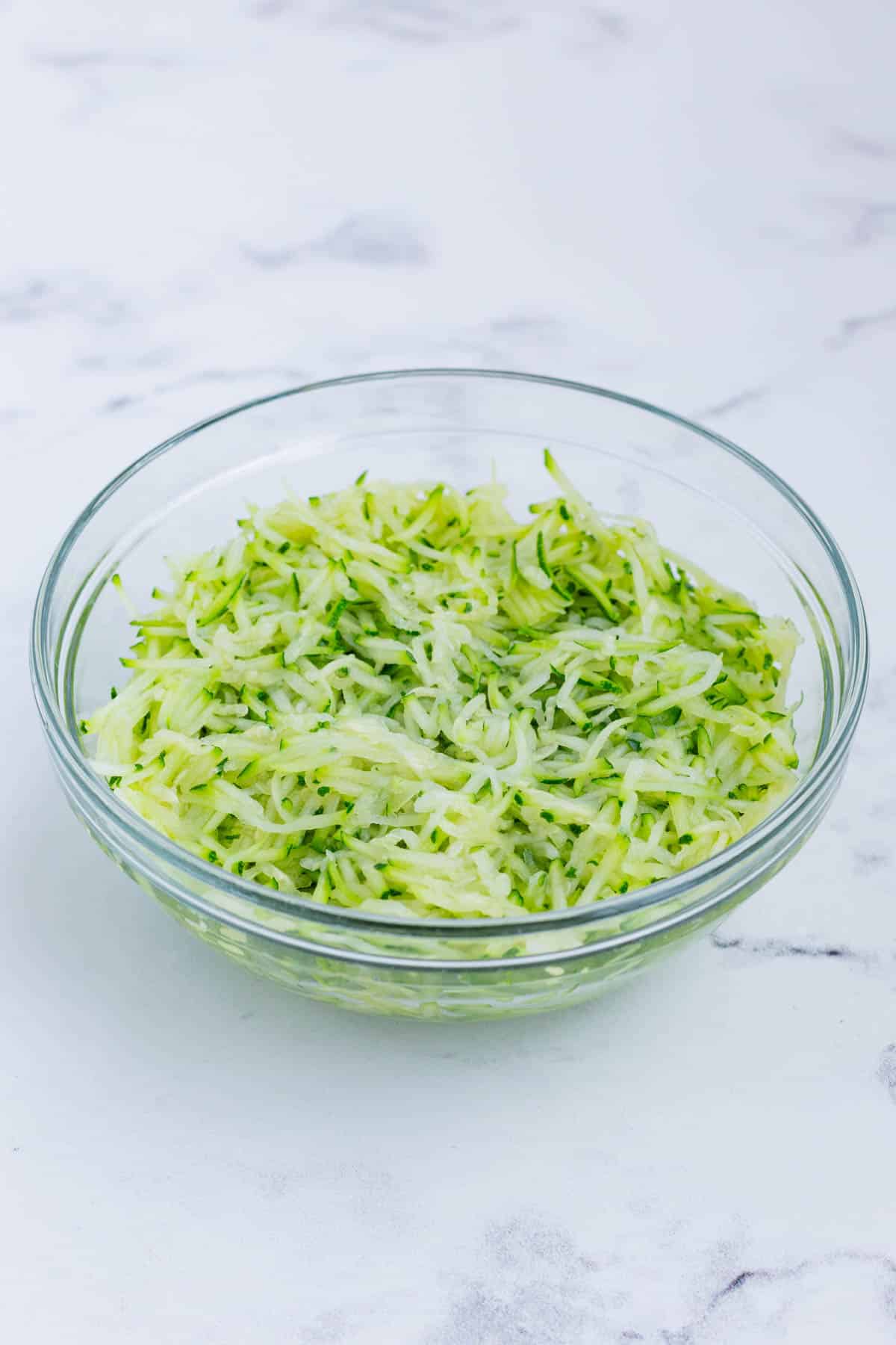 A bowl of shredded zucchini is ready to add to the batter.