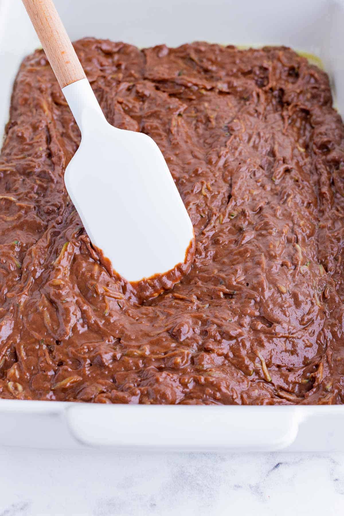 Zucchini brownie batter is spread in a pan.