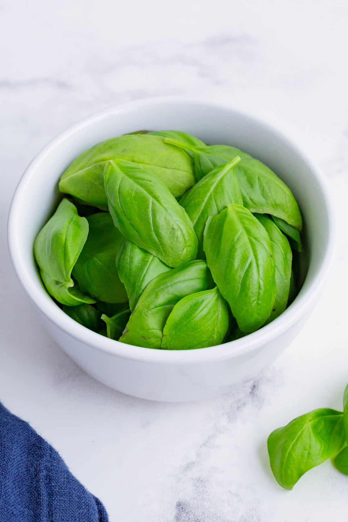 A bowl of fresh basil leaves are ready to dry.