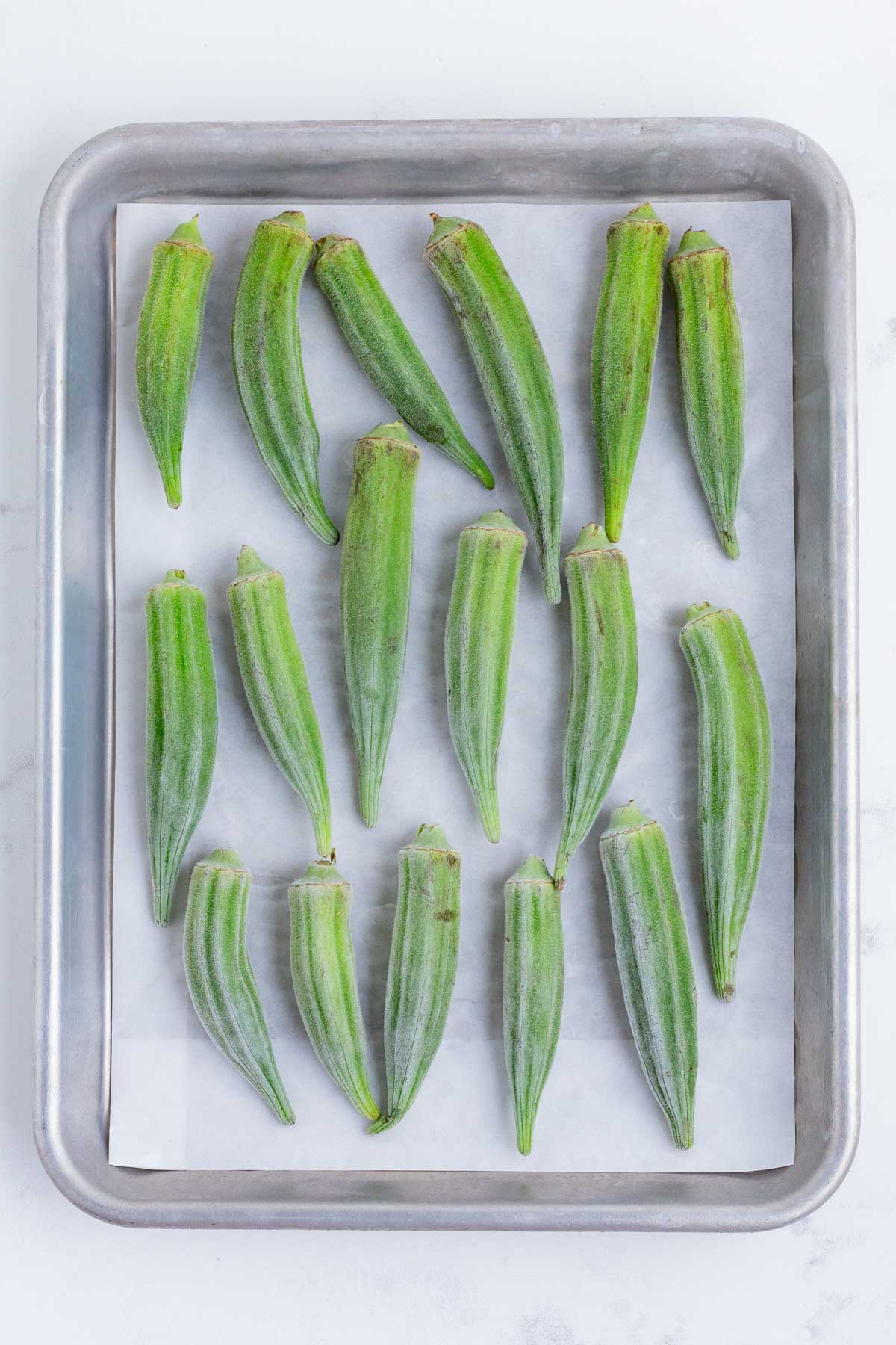 Whole okra is flash-frozen on a pan.