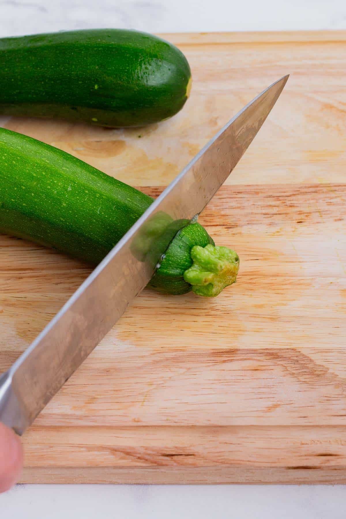 A sharp knife slices fresh zucchini.
