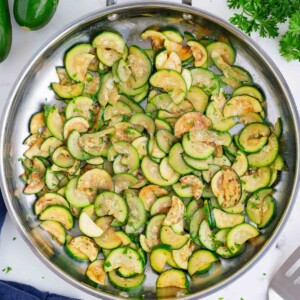 Zucchini is sauteed in a stainless steel skillet.