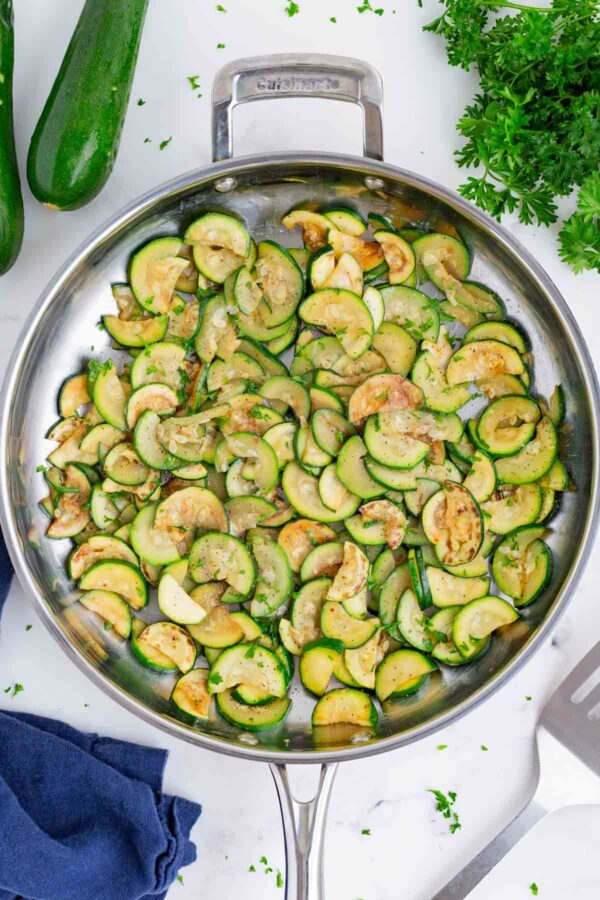 Zucchini is sauteed in a stainless steel skillet.