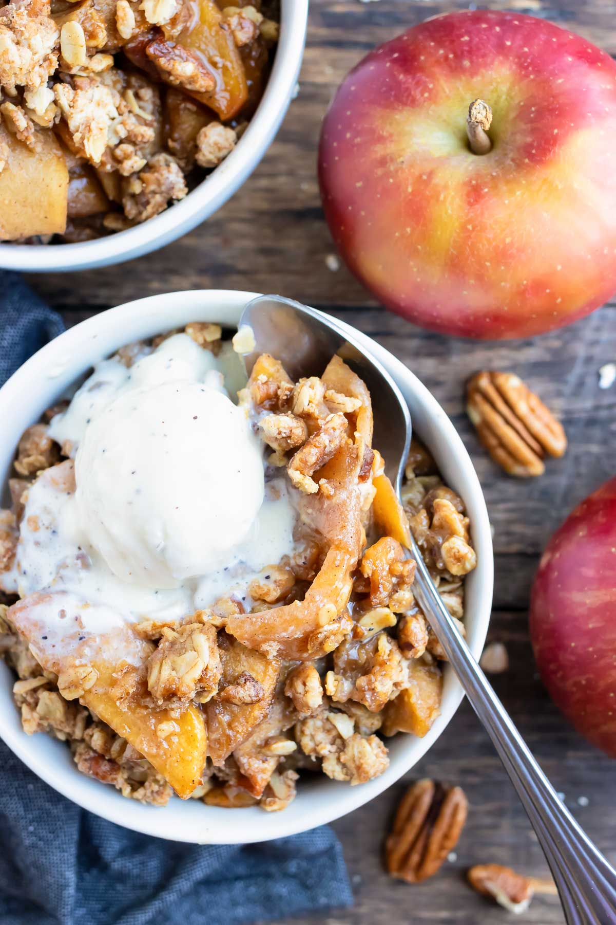Two dessert bowls full of a gluten-free apple crisp recipe with oats and pecans.