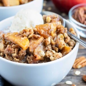 Two dessert bowls full of a gluten-free apple crisp recipe with an oatmeal and pecan crumb topping.