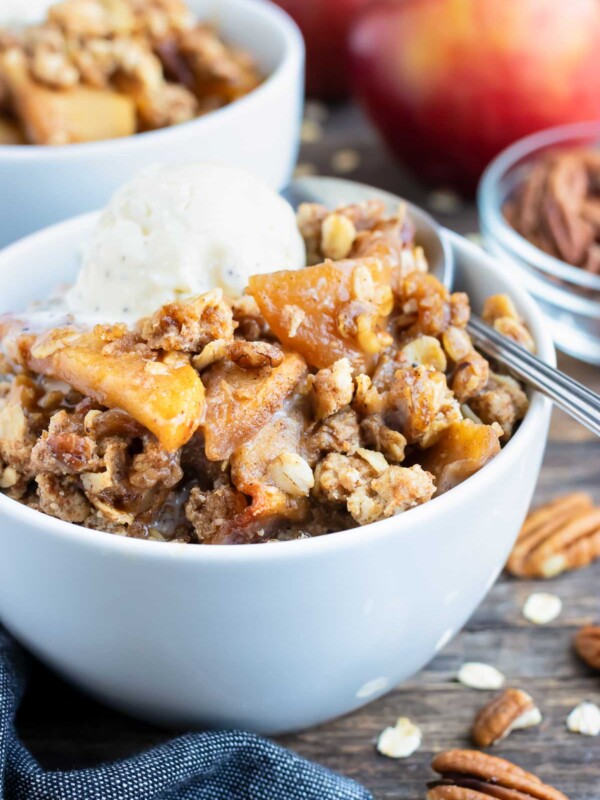 Two dessert bowls full of a gluten-free apple crisp recipe with an oatmeal and pecan crumb topping.