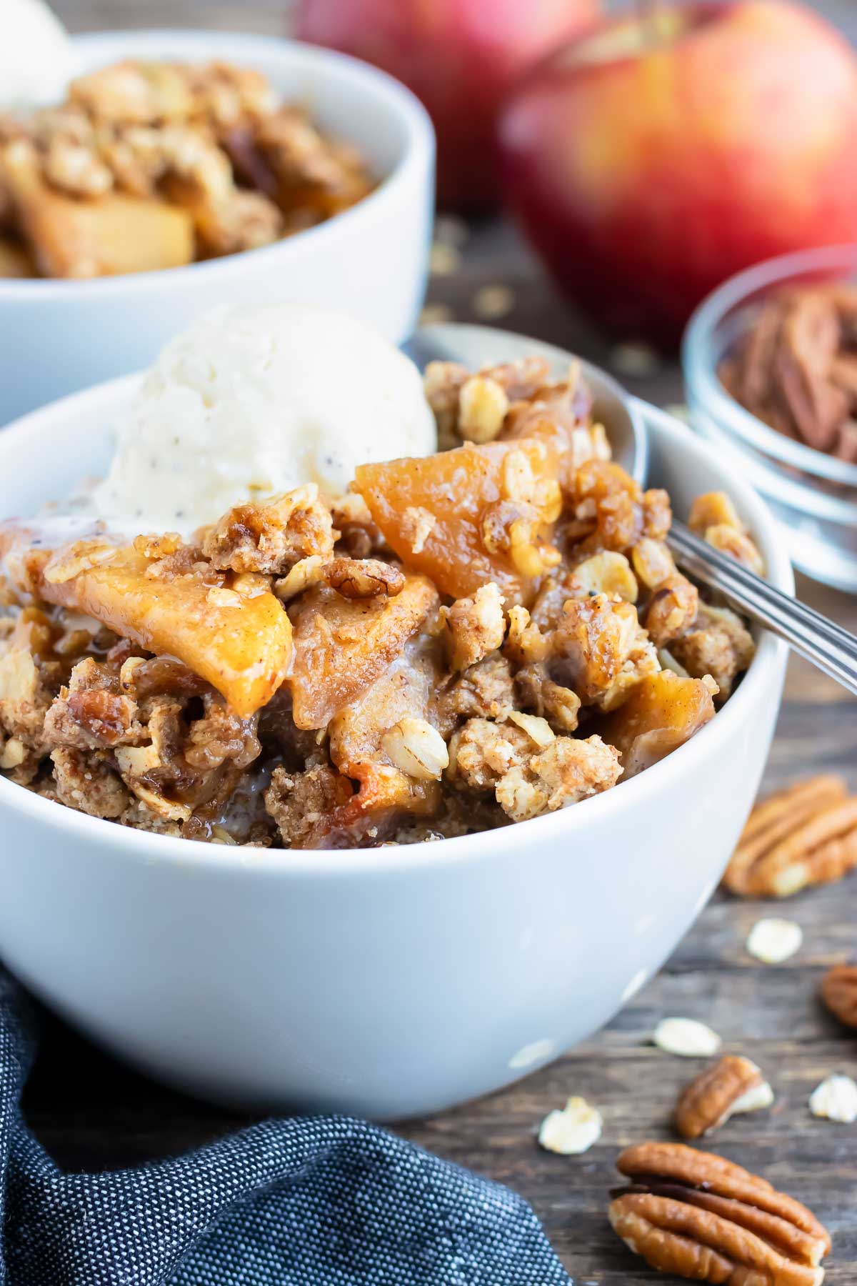 Two dessert bowls full of a gluten-free apple crisp recipe with an oatmeal and pecan crumb topping.