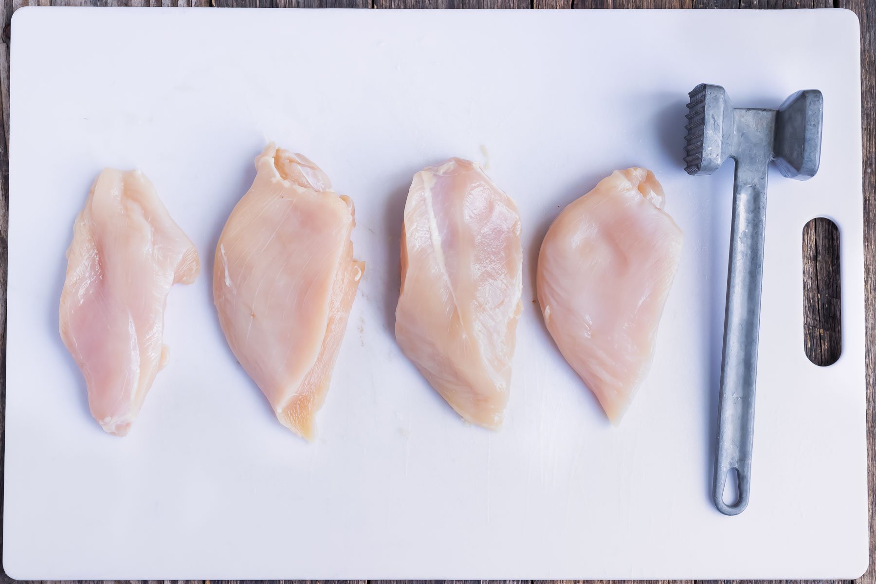 Four organic chicken breasts that have been pounded and tenderized for a recipe.