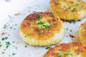 A ceramic skillet full of fried goat cheese balls with parsley sprinkled on top.