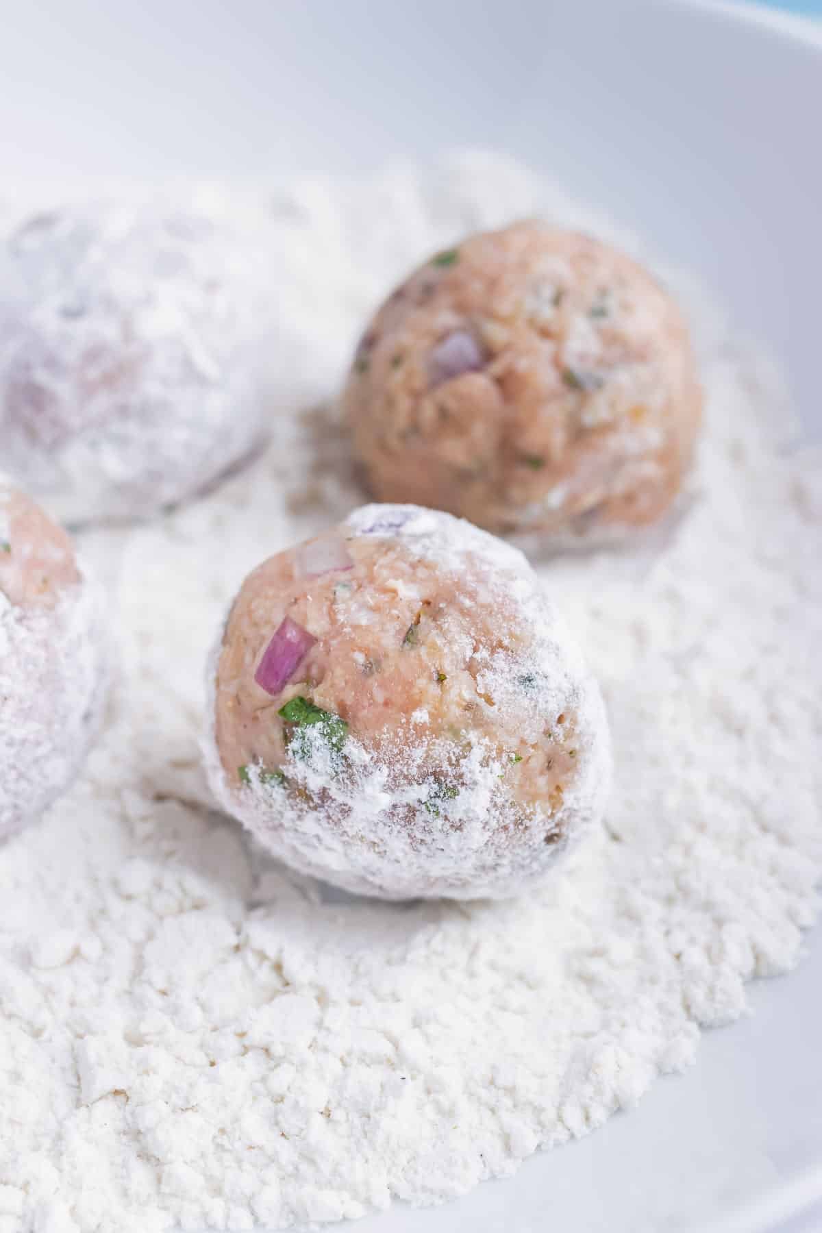Greek turkey meatballs are rolled in a light layer of flour before being cooked.