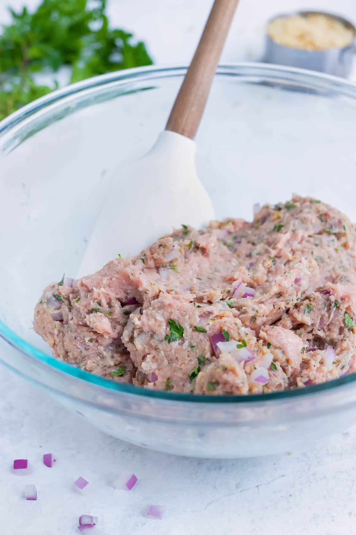 A spatula mixes ground turkey and other ingredients in this easy, low-carb, gluten-free meatball recipe.