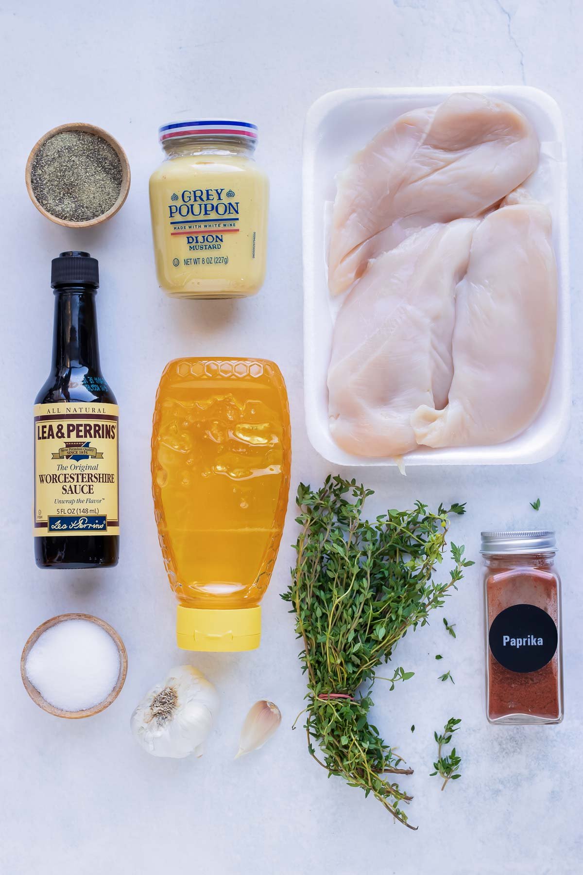 Honey, mustard, thyme, paprika, salt, and garlic as ingredients for a recipe.