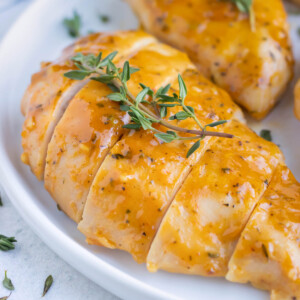 Honey mustard baked chicken breasts on a white dinner plate.
