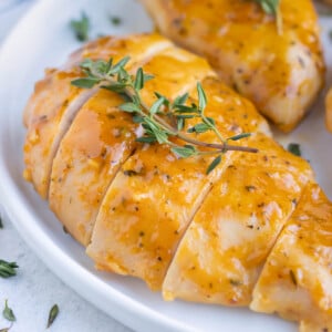 Honey mustard baked chicken breasts on a white dinner plate.