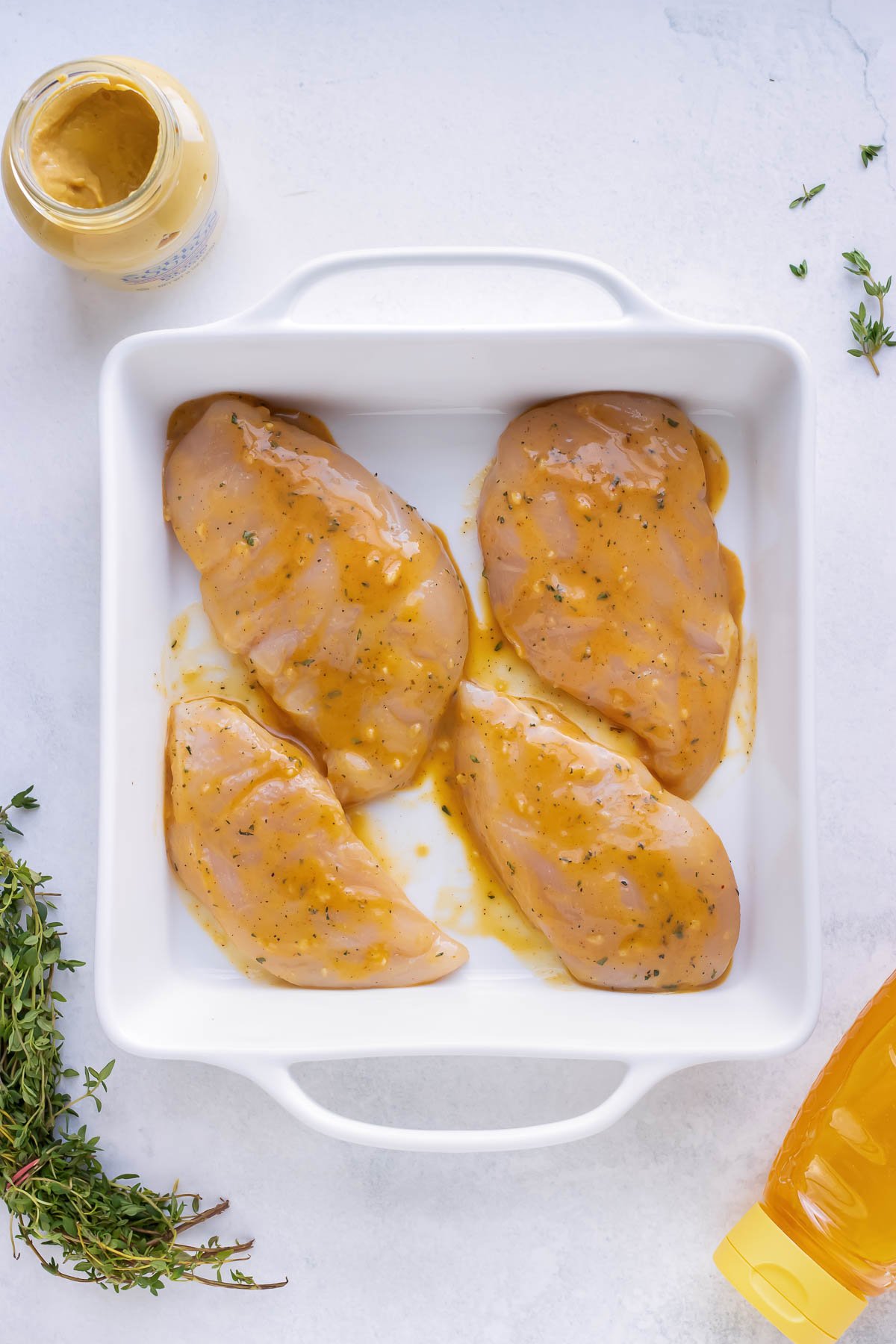 A casserole dish full of raw chicken that has been marinading before cooking.