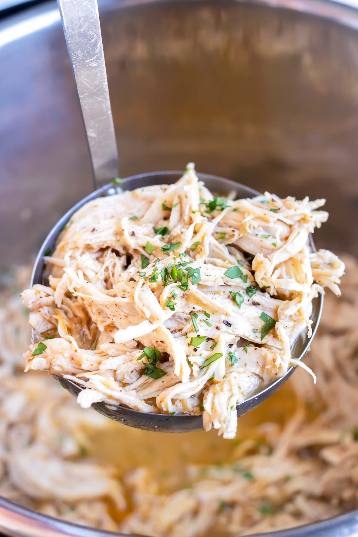 A ladle full of shredded salsa chicken from an Instant Pot bowl.