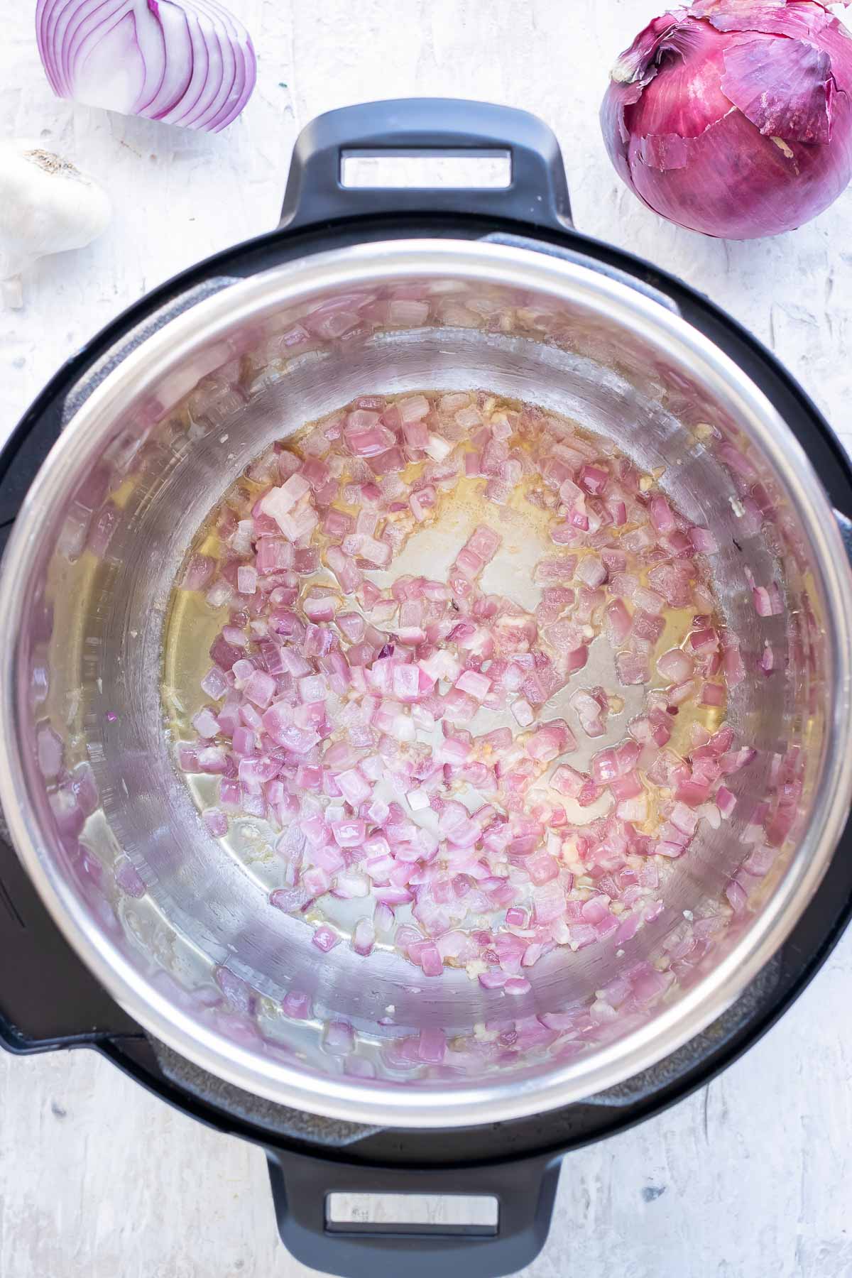 Garlic is added to the Instant Pot with the onion.