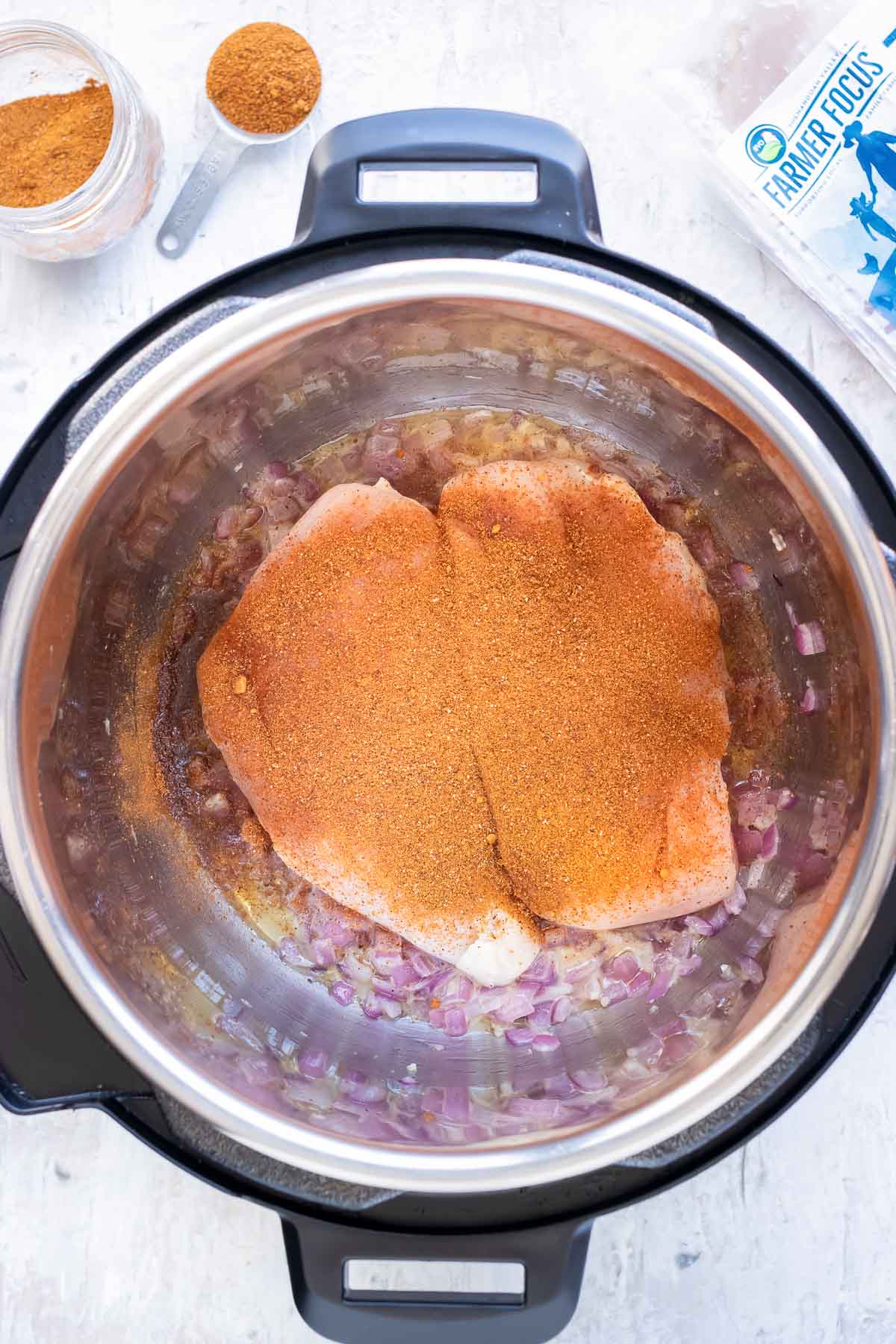 Taco Seasoning is sprinkled over the chicken breast in the Instant Pot.