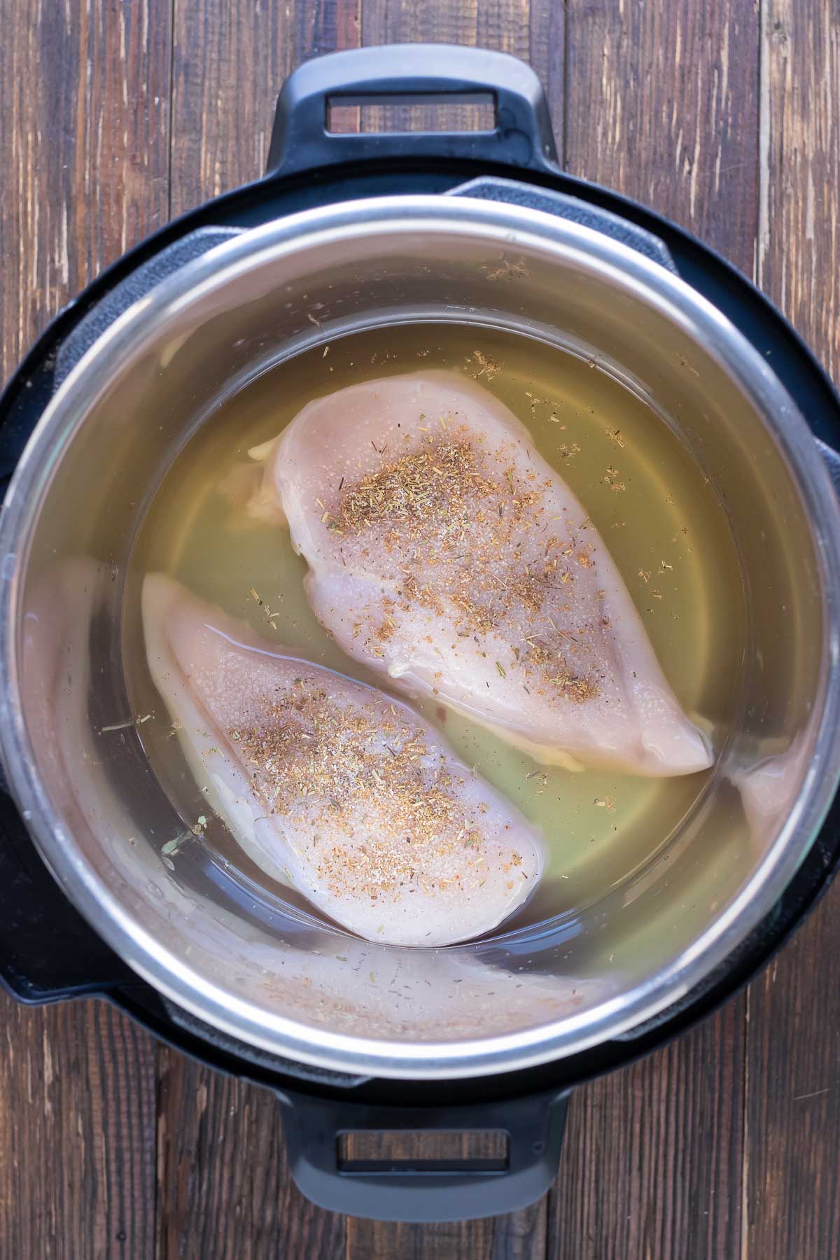 Chicken and seasonings are added to the oil in the Instant Pot.