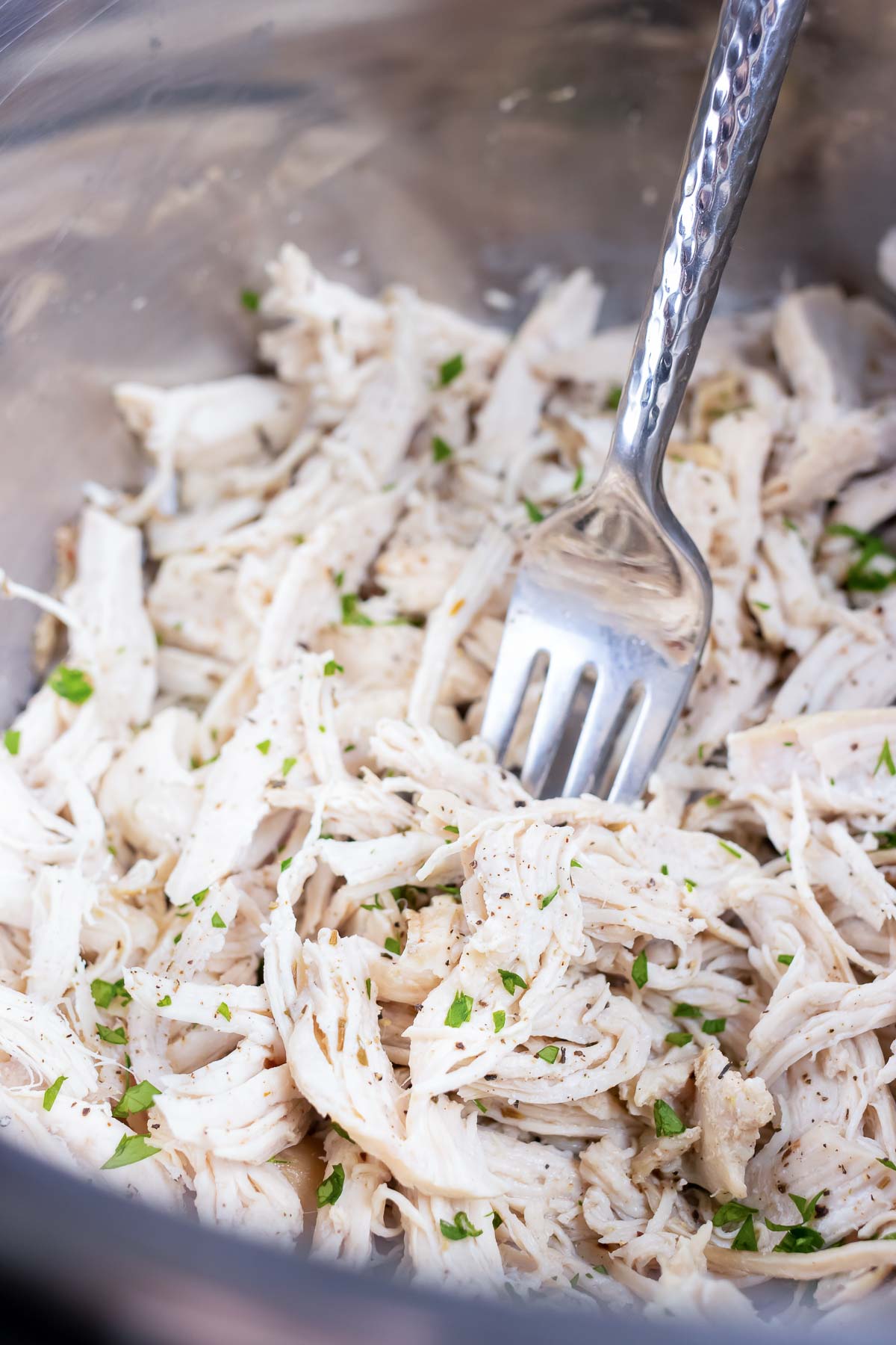 A stainless steel pot that is full of pulled chicken that has been pressure cooked.