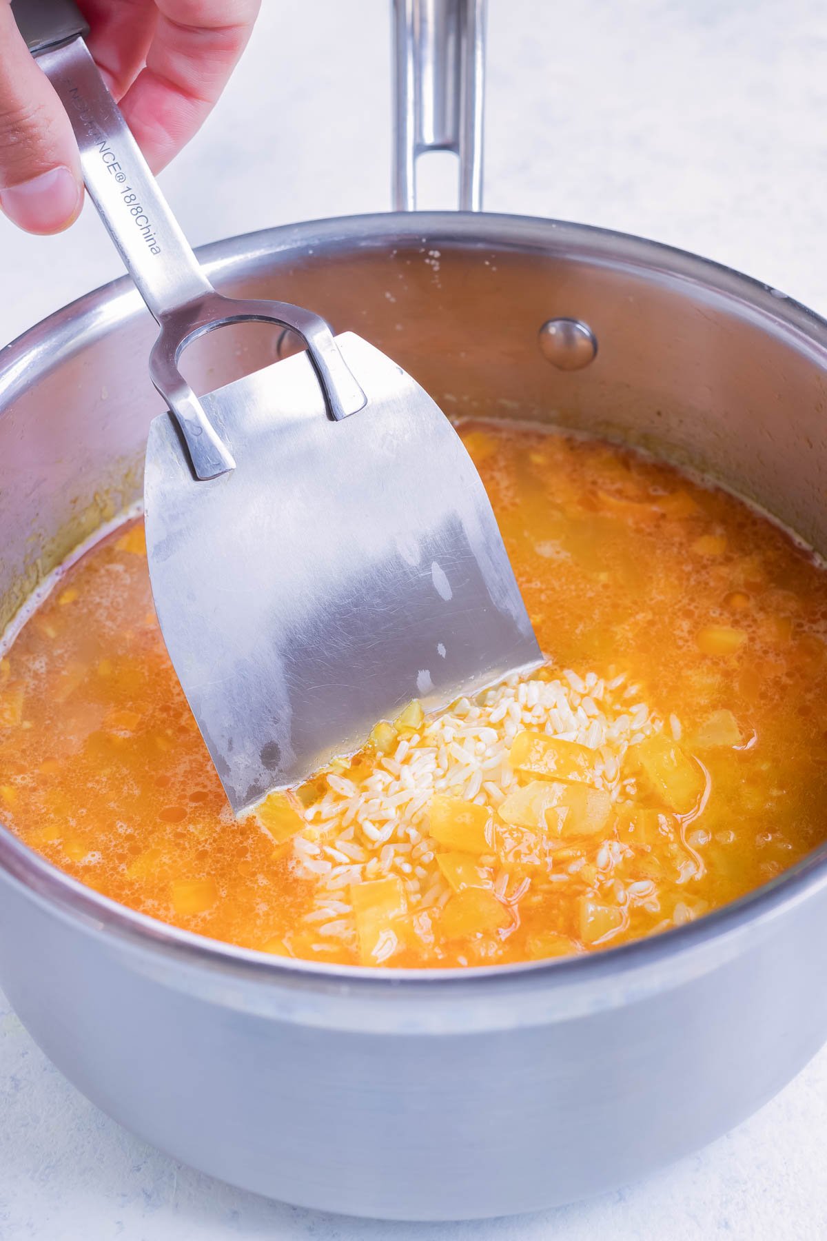 Rice and broth are added to the seasoned onions.