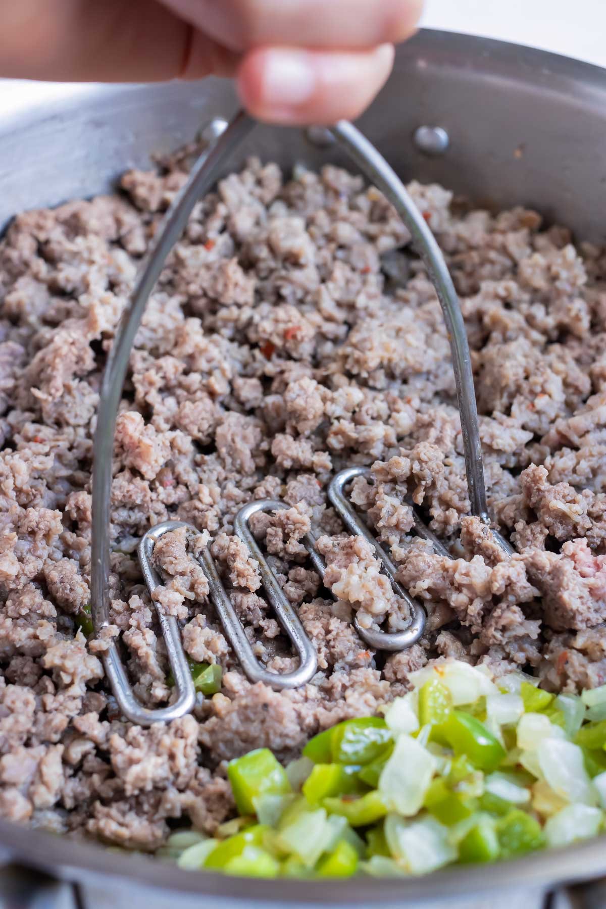 Ground beef is cooked in a skillet on the stove.