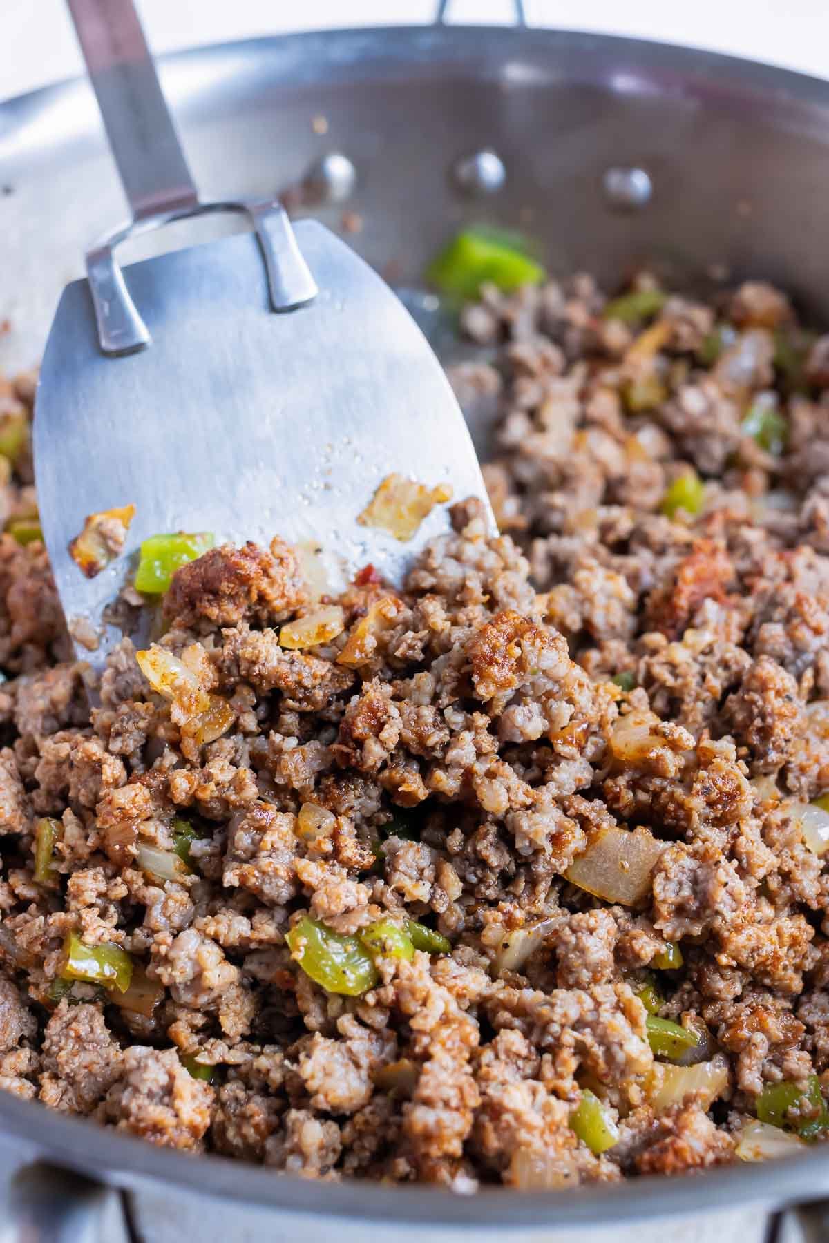 Ground beef is added to the sautéed vegetables and cooked in the skillet.