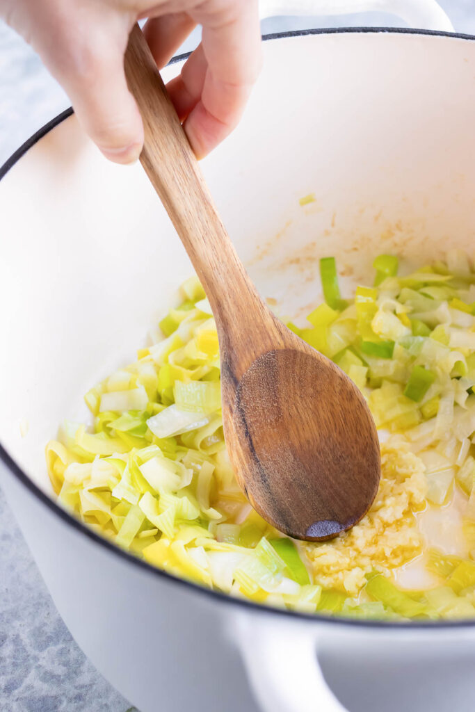 Chopped leeks are sauteed in a Dutch oven.