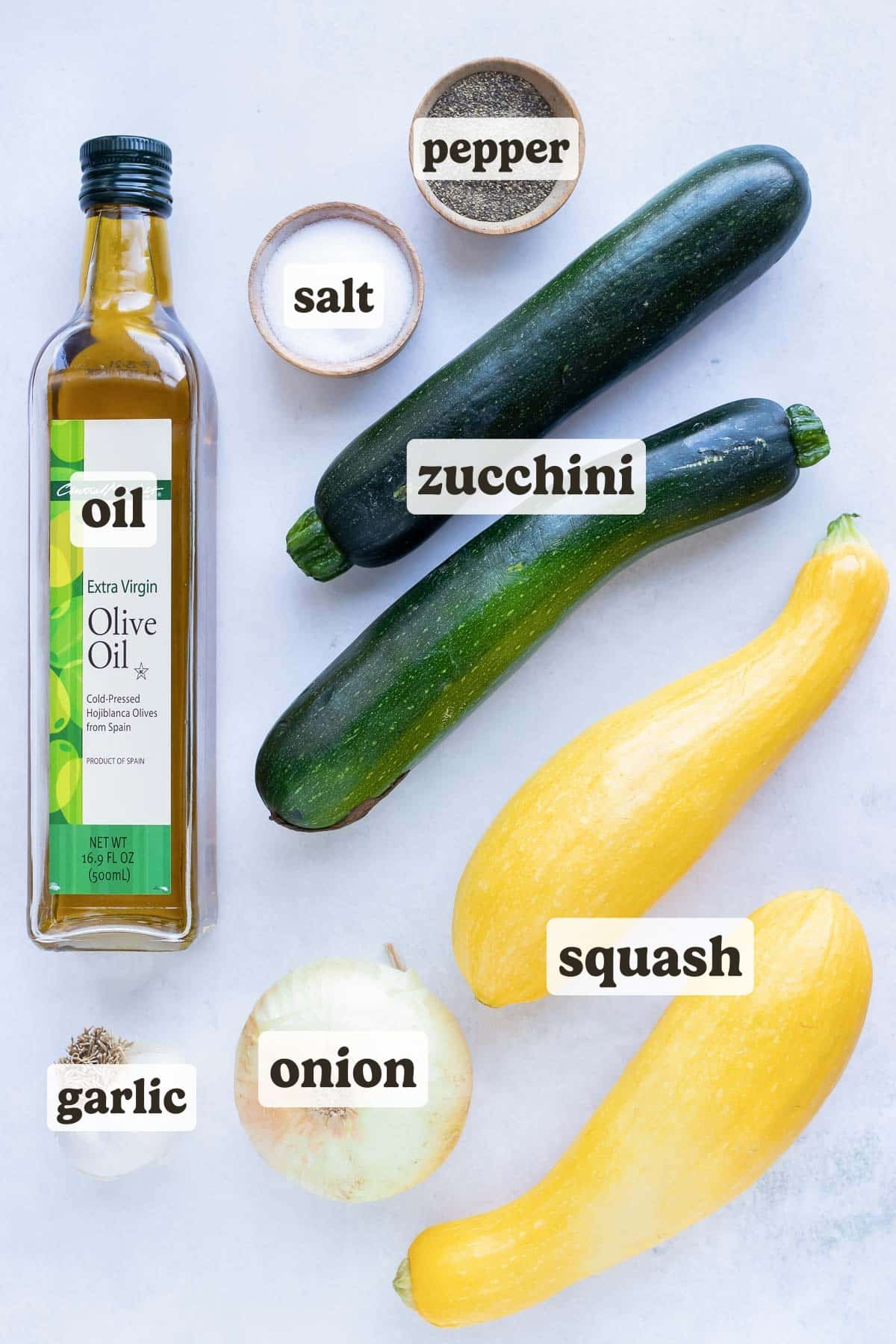 Zucchini, yellow squash, salt, pepper, onion, oil, and garlic ingredients for a sauteed zucchini and squash side dish recipe.