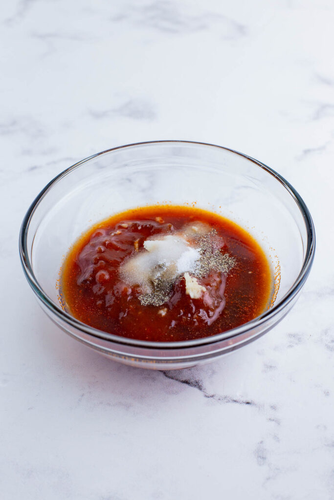 Apricot preserves, barbecue sauce, and seasonings added to a glass bowl for a homemade apricot glaze.